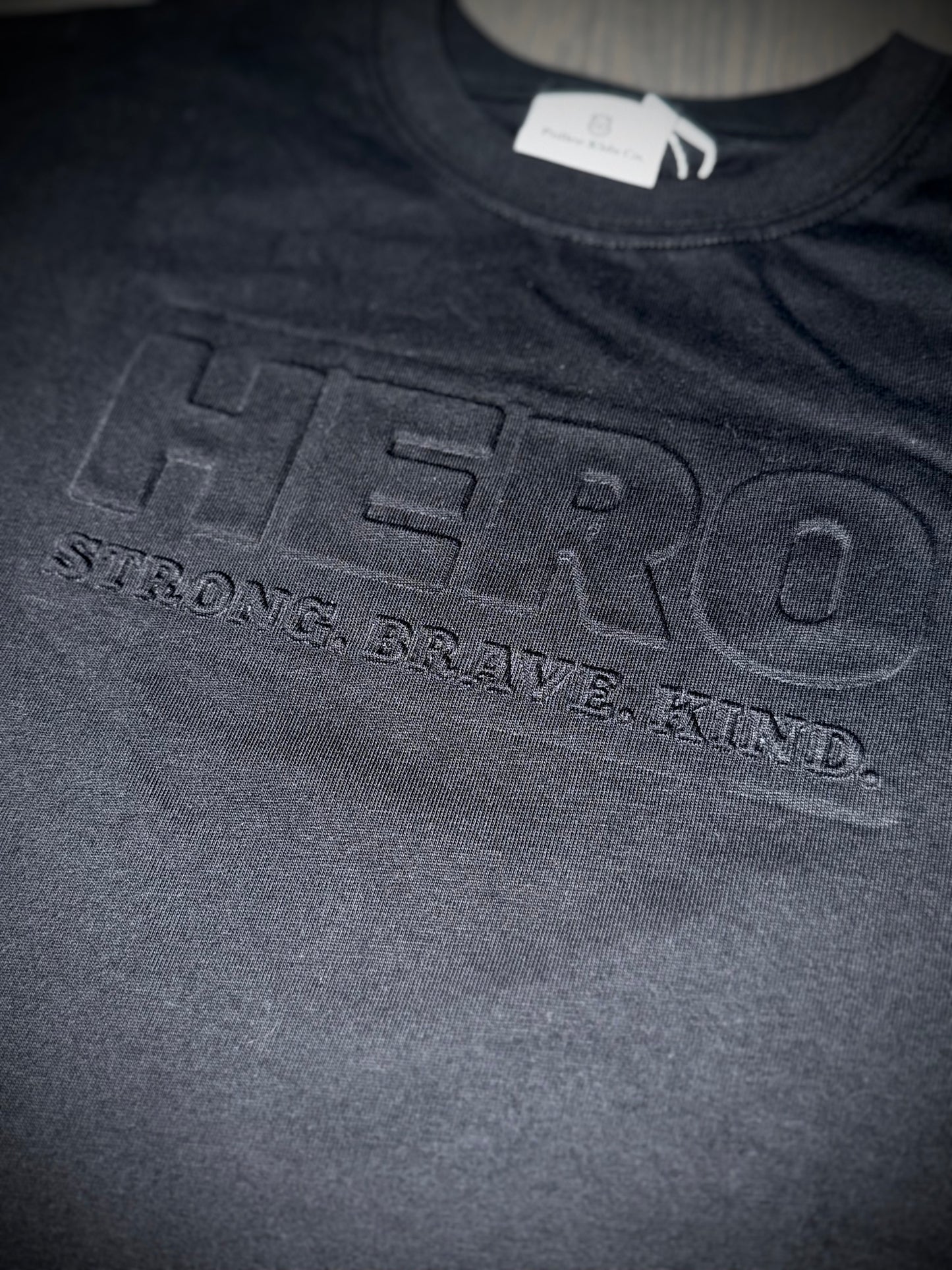 “Raised to Be a Hero” Embossed Tee